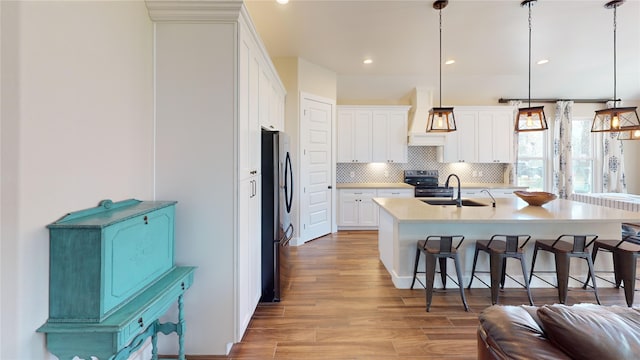 kitchen featuring a kitchen breakfast bar, tasteful backsplash, a sink, stainless steel appliances, and white cabinetry