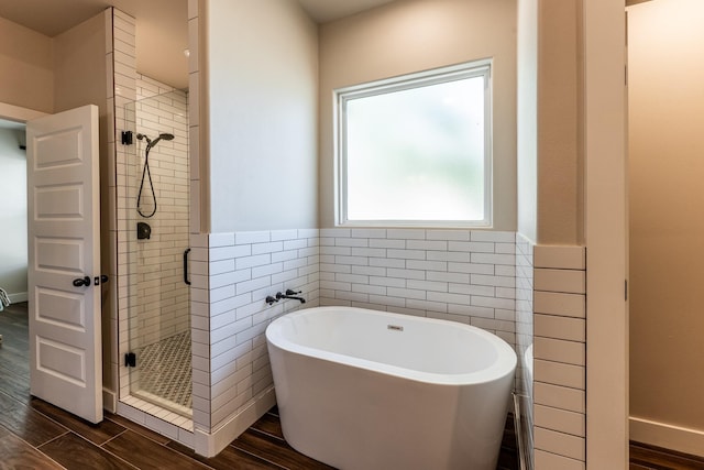 full bathroom with wood tiled floor, a freestanding bath, a stall shower, and tile walls