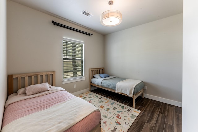 bedroom with baseboards, visible vents, and wood finished floors