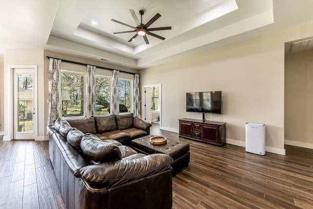 living area featuring baseboards, a raised ceiling, ceiling fan, and dark wood-style floors
