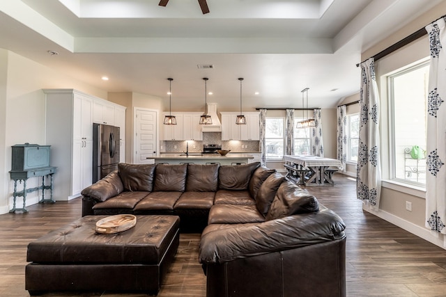 living area with visible vents, ceiling fan, dark wood-style floors, recessed lighting, and a tray ceiling