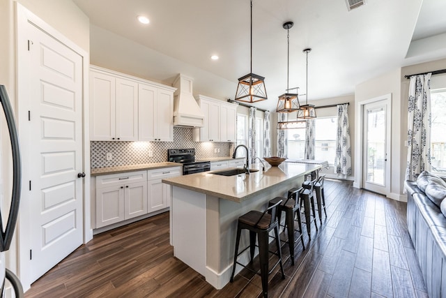 kitchen featuring dark wood-style flooring, a sink, an island with sink, stainless steel appliances, and white cabinetry