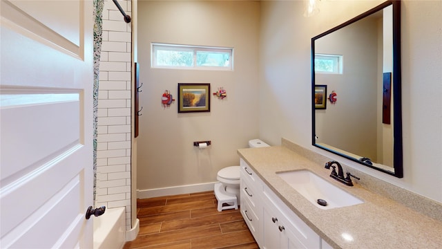 full bath featuring vanity, plenty of natural light, wood finished floors, and toilet
