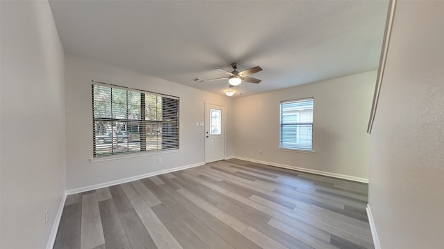 unfurnished room featuring ceiling fan, wood finished floors, and baseboards