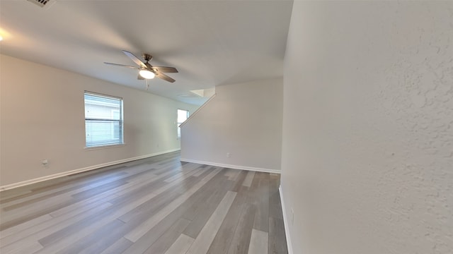 interior space with baseboards, wood finished floors, and a ceiling fan