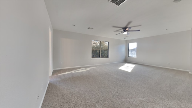 empty room with baseboards, visible vents, ceiling fan, and carpet