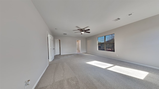 empty room with visible vents, ceiling fan, light colored carpet, and baseboards
