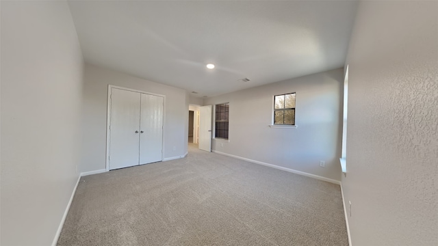 unfurnished bedroom featuring baseboards, visible vents, a closet, and carpet flooring