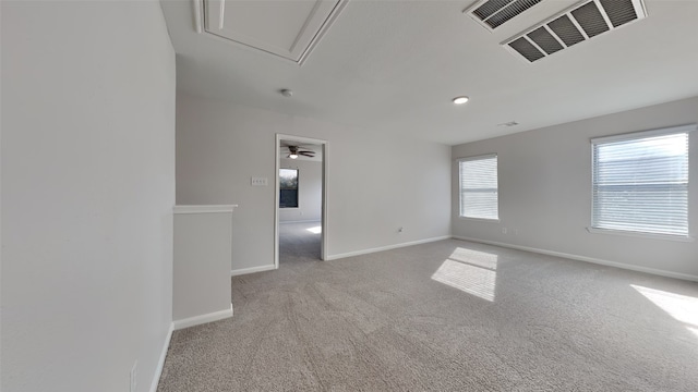 spare room featuring baseboards, visible vents, attic access, and light colored carpet