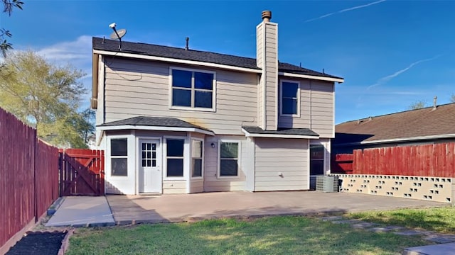 rear view of property featuring a chimney, a gate, a fenced backyard, and a patio area