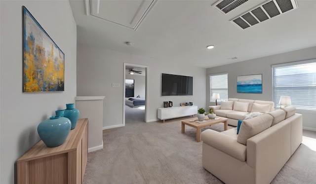 living room featuring attic access, a ceiling fan, visible vents, light carpet, and baseboards