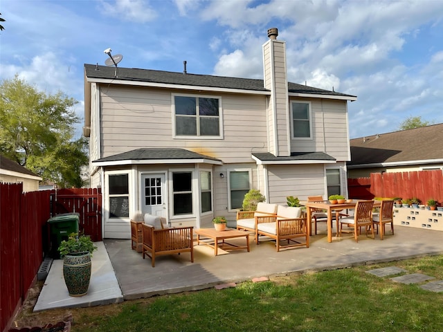 rear view of house with a patio, an outdoor living space, a chimney, and a fenced backyard