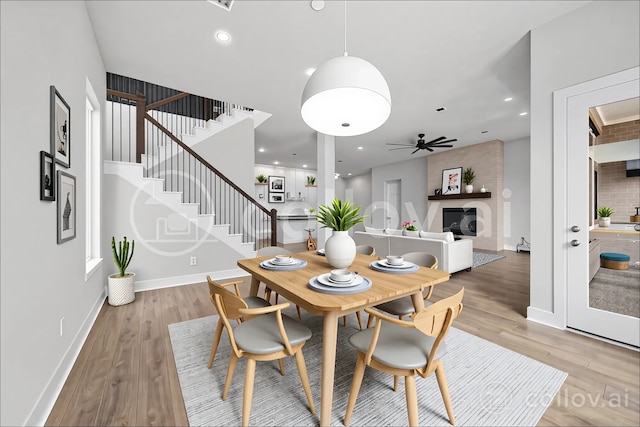4411 Windy Oaks Dr, Fulshear, TX 77441 - dining space featuring a large fireplace, stairway, ceiling fan, light wood-style floors, and recessed lighting
