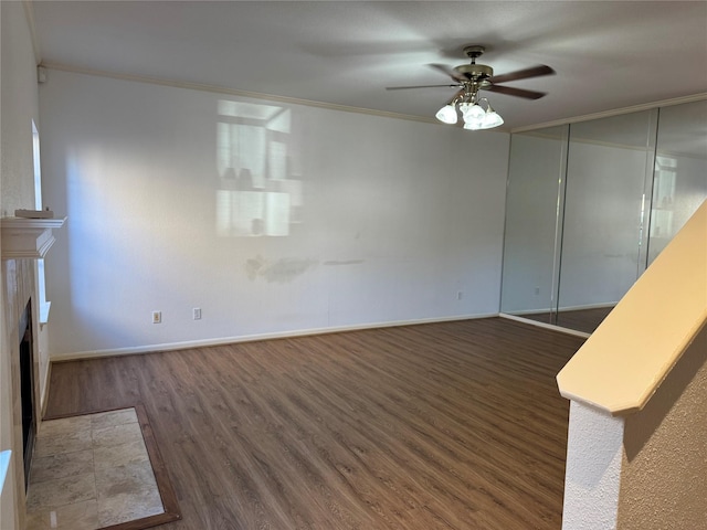 9850 Pagewood Ln Unit 1001, Houston, TX 77042 - unfurnished living room featuring dark wood-style floors, crown molding, ceiling fan, a tiled fireplace, and baseboards