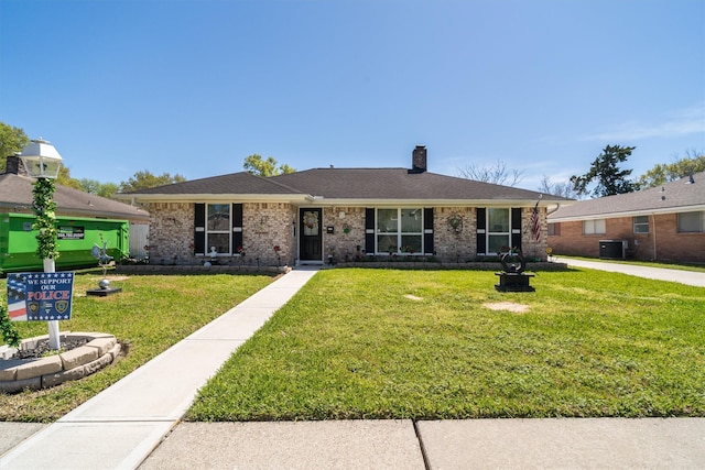 single story home featuring a chimney, a front yard, and brick siding