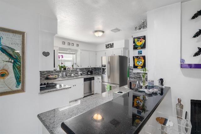 kitchen featuring visible vents, a sink, white cabinetry, tasteful backsplash, and appliances with stainless steel finishes