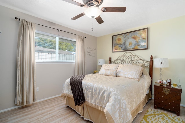 bedroom with baseboards, a ceiling fan, and light wood-style floors