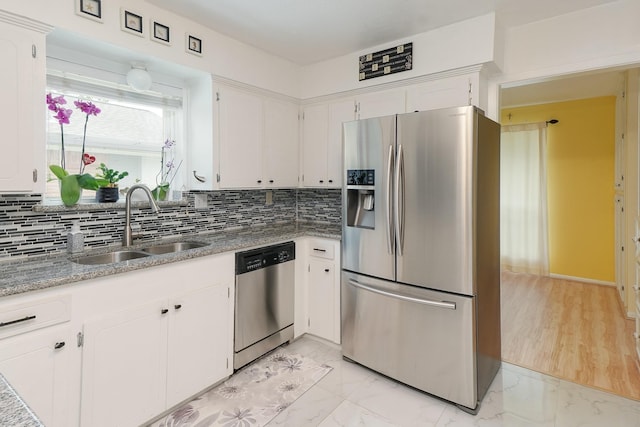kitchen featuring a sink, stainless steel appliances, white cabinetry, backsplash, and marble finish floor