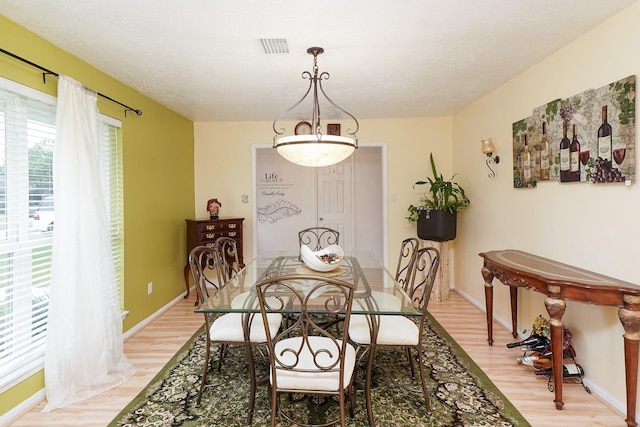 dining room with light wood finished floors, baseboards, and visible vents