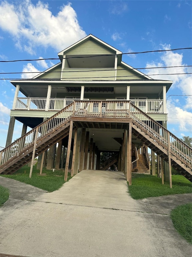 205 Rue Orleans St, Baytown, TX 77520 - coastal inspired home featuring a carport, a porch, stairway, and concrete driveway