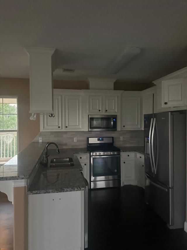 205 Rue Orleans St, Baytown, TX 77520 - kitchen featuring white cabinetry, decorative backsplash, a sink, a peninsula, and appliances with stainless steel finishes
