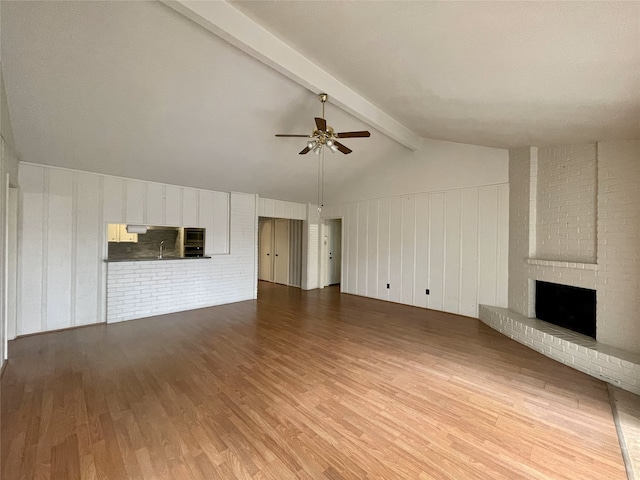 10415 Huntington Wood Dr, Houston, TX 77099 - unfurnished living room with a fireplace, ceiling fan, wood finished floors, a sink, and vaulted ceiling with beams