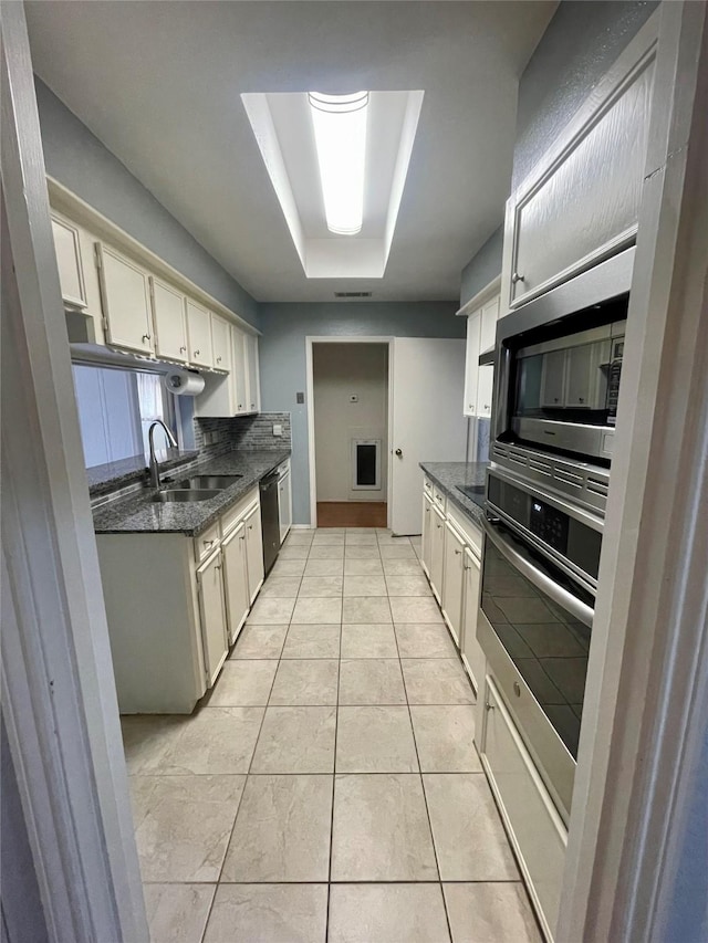 10415 Huntington Wood Dr, Houston, TX 77099 - kitchen with light tile patterned flooring, dark stone counters, appliances with stainless steel finishes, a sink, and a tray ceiling