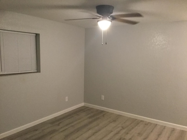 empty room with baseboards, a ceiling fan, and wood finished floors