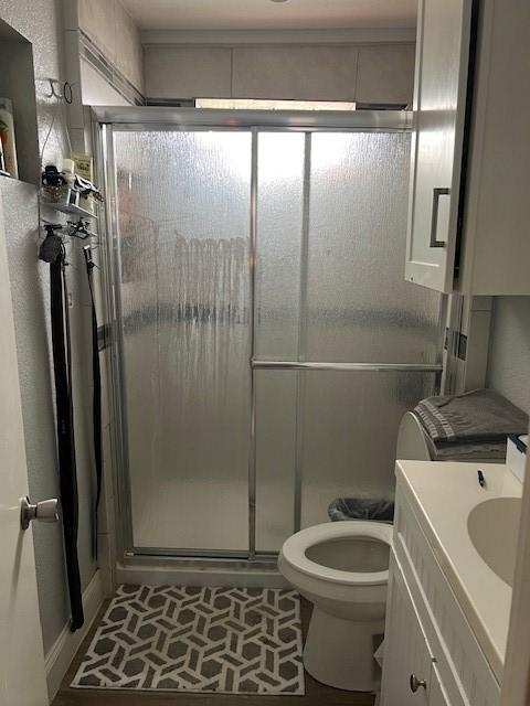full bath with toilet, a stall shower, and vanity