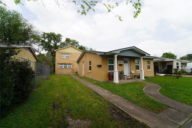 view of front facade with brick siding, a front yard, and fence
