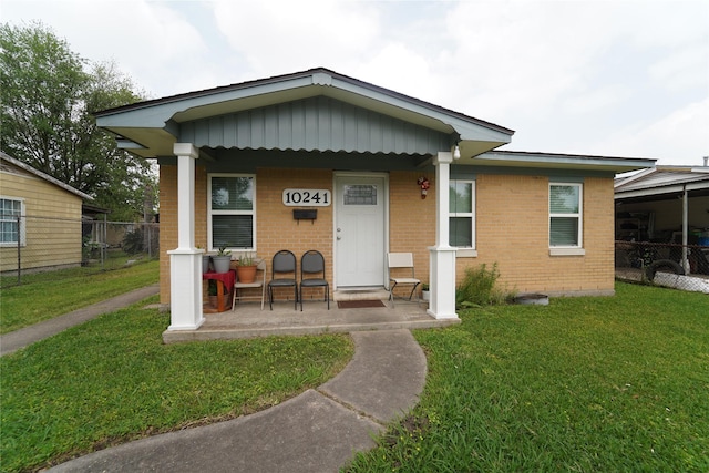 view of front of property featuring brick siding, a front yard, a porch, and fence