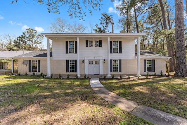 neoclassical / greek revival house featuring brick siding and a front yard