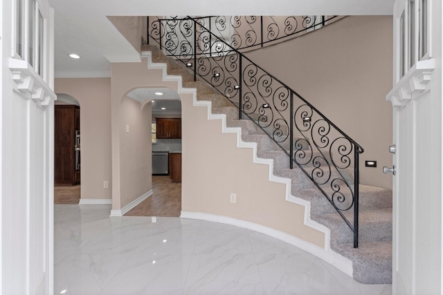 staircase with crown molding, recessed lighting, baseboards, marble finish floor, and arched walkways