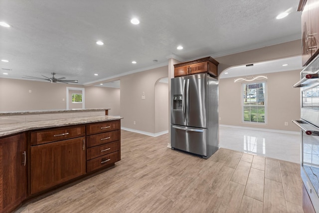 kitchen featuring light wood-style flooring, stainless steel fridge with ice dispenser, arched walkways, a ceiling fan, and light stone countertops
