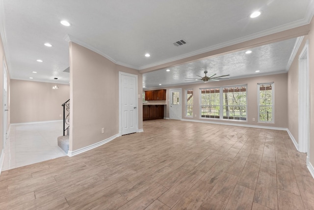 unfurnished living room featuring crown molding, light wood-type flooring, baseboards, ceiling fan, and visible vents