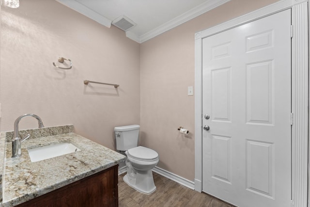 half bath with toilet, vanity, wood finished floors, visible vents, and ornamental molding