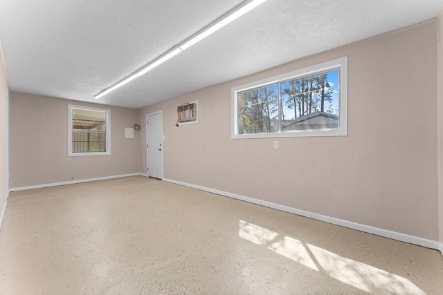 empty room featuring baseboards, a textured ceiling, and a wall mounted air conditioner
