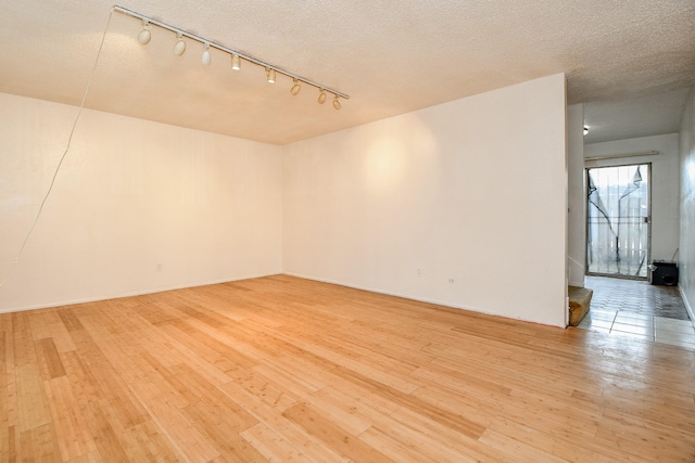 7885 Cook Rd, Houston, TX 77072 - empty room with light wood finished floors, track lighting, and a textured ceiling