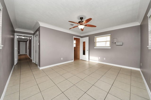 empty room with a textured ceiling, visible vents, baseboards, ornamental molding, and a ceiling fan