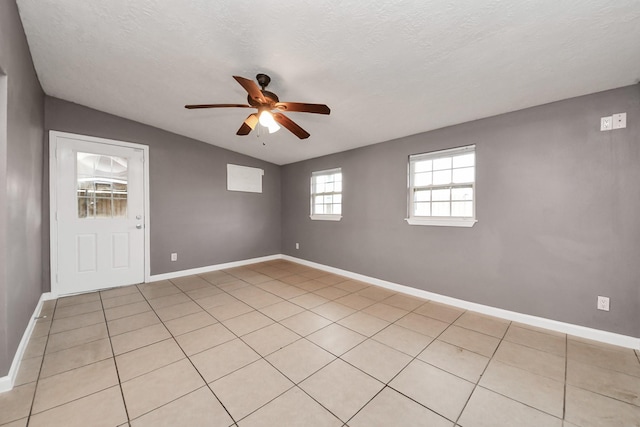 empty room featuring baseboards, vaulted ceiling, ceiling fan, and a textured ceiling