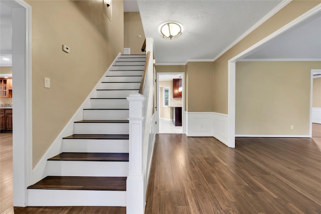 6522 Coral Ridge Rd, Houston, TX 77069 - staircase featuring a wainscoted wall, crown molding, wood finished floors, and a textured ceiling