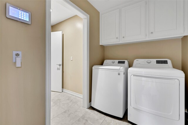 6522 Coral Ridge Rd, Houston, TX 77069 - laundry room featuring baseboards, washing machine and clothes dryer, cabinet space, and light tile patterned floors