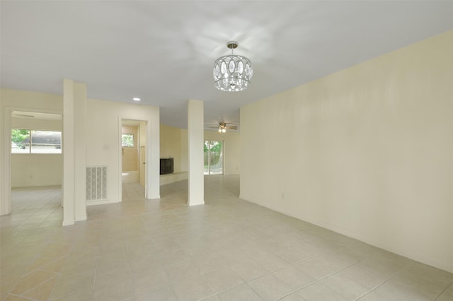unfurnished living room featuring ceiling fan with notable chandelier, visible vents, a wealth of natural light, and light tile patterned floors