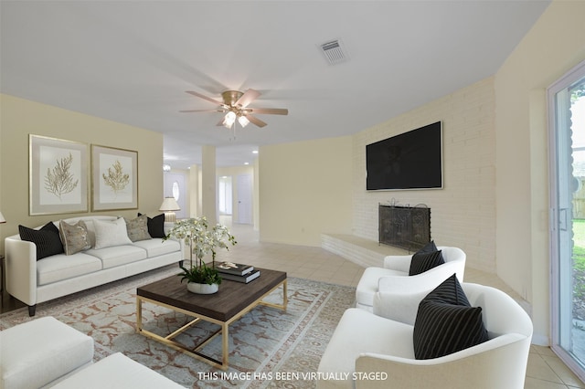 living area featuring a brick fireplace, visible vents, tile patterned floors, and a ceiling fan