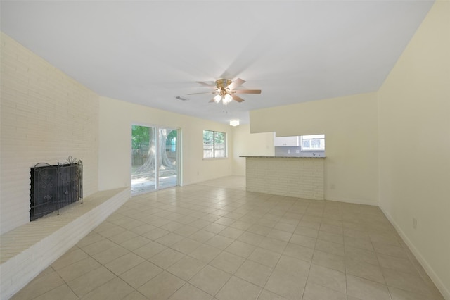unfurnished living room with ceiling fan, a brick fireplace, visible vents, and light tile patterned floors