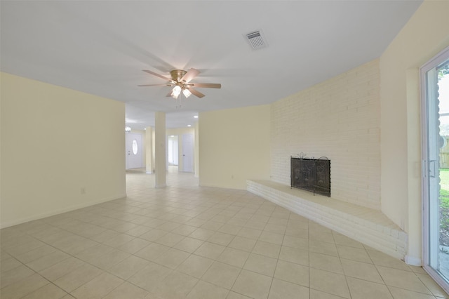 unfurnished living room featuring visible vents, a ceiling fan, light tile patterned floors, baseboards, and a brick fireplace