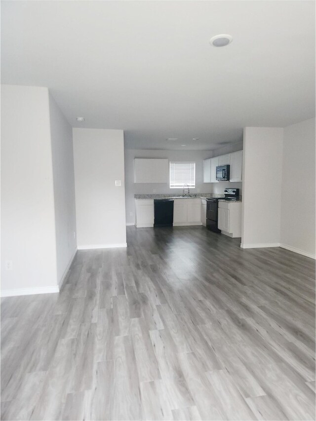2395 Monroe St, Beaumont, TX 77703 - unfurnished living room featuring light wood-style flooring, a sink, and baseboards