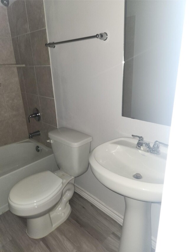 2395 Monroe St, Beaumont, TX 77703 - bathroom with baseboards, shower / washtub combination, toilet, and wood finished floors