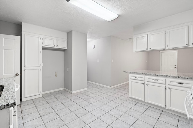 12109 22nd St, Santa Fe, TX 77510 - kitchen with a textured ceiling, white cabinets, light stone countertops, and light tile patterned floors