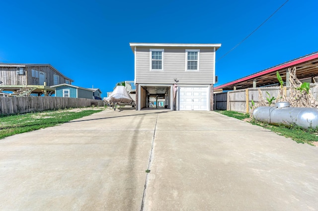 rear view of property with fence, driveway, and a garage